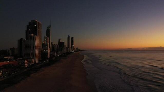 Aerial flyout from Surfers Paradise beach to ocean, with full view of coastal cityscape. Gold Coast, Australia.
