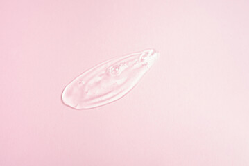 Smear of a transparent gel on a pink background. Texture of liquid cosmetic gel.