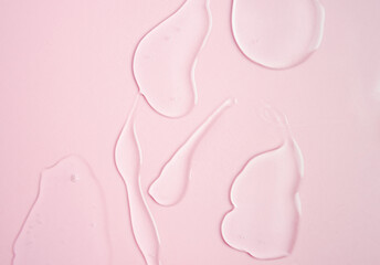 Samples of a transparent gel on a pink background. Texture of liquid cosmetic gel.
