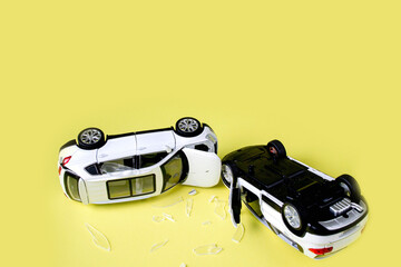 Two mini toy car crash on yellow background, incident, car traffic accident.