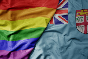 big waving realistic national colorful flag of Fiji and rainbow gay pride flag .