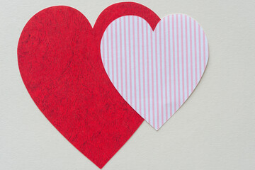 red paper heart and smaller striped pink paper heart on blank paper