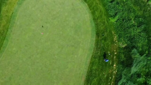 Drone footage of a man playing golf on a sunny day