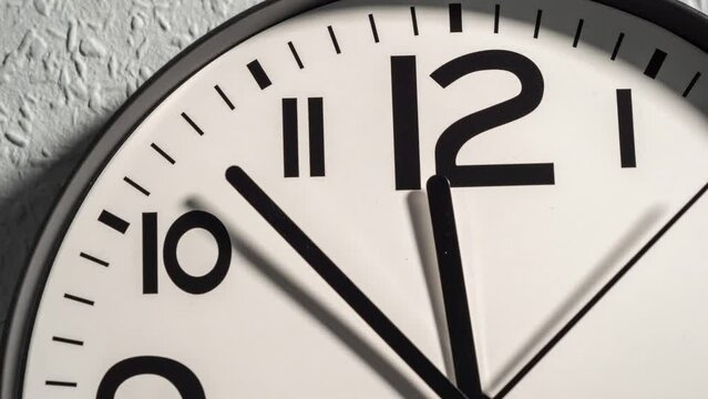 Timelapse of a wall clock. The time is twelve o'clock. Wall clock on a background on a gray wall.