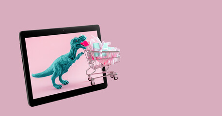 Blue dinosaur with shopping cart on digital tablet screen. Online sale and shopping concept. Place...