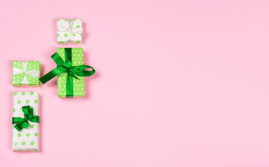 Green and white polka dot decorative gift boxes on pink background. Copy space.