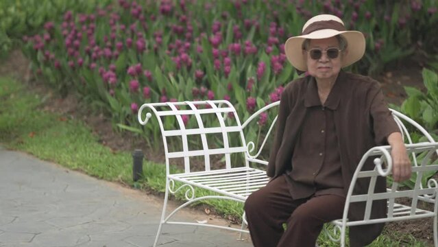 old elderly elder senior woman resting relaxing in flower garden