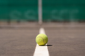 Yellow tennis ball placed on white mark on sports ground in daylight - Powered by Adobe