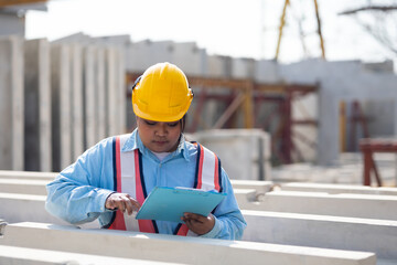 African american women foreman checking quality of prefabricated concrete wall. Plus size female worker wearing safety hardhat working at heavy Prefabricated concrete walls manufacturing factory