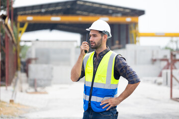 radio transmitter. Hispanic latin architect construction Engineering man in hardhat talking on walkie talkie at factory facilities. Heavy Industry Manufacturing Factory. Prefabricated concrete walls