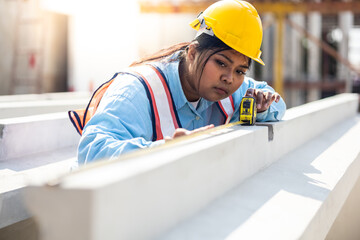 Yellow tape measure construction tools. Plus size female worker wearing safety hardhat inspec quality control at heavy Prefabricated concrete walls manufacturing factory - obrazy, fototapety, plakaty