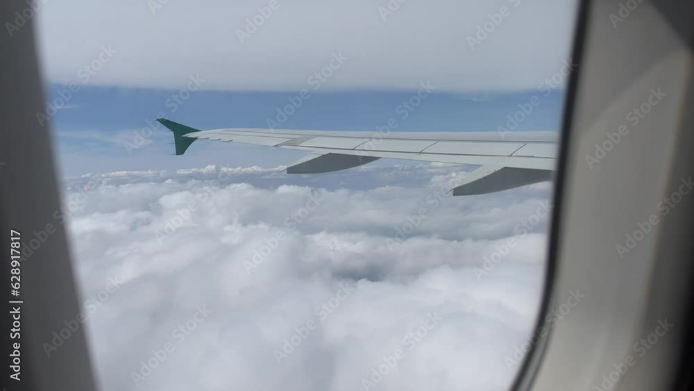 Poster view from airplane window flying between two layers of white clouds