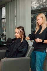 A hairdresser cuts a blonde's hair in a beauty salon. Women's haircut