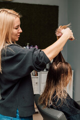 Fototapeta premium A hairdresser cuts a blonde's hair in a beauty salon. Women's haircut