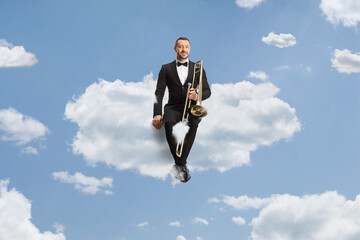 Male musician in a black suit and bow-tie sitting on a cloud
