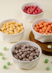 White bowls filled with different colored cereals on a white surface