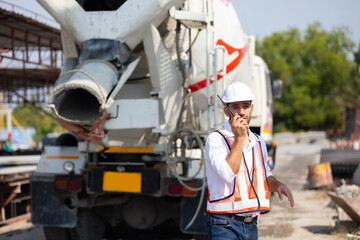 Concrete mixer truck on background. radio transmitter. Hispanic latin architect construction man in hardhat talking on walkie talkie at Heavy Industry Manufacturing. Prefabricated concrete walls