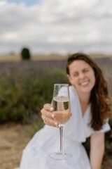 Caucasian woman in a lavender field, holding a glass of Prosecco in her hand