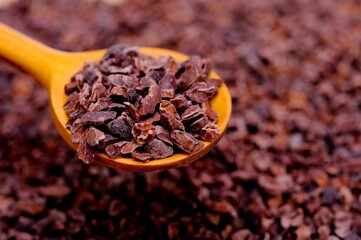 Close-up of organic raw cacao nibs in a spoon on a table
