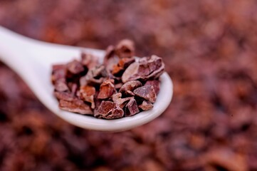 Close-up of organic raw cacao nibs in a spoon on a table