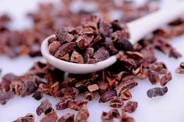 Close-up of organic raw cacao nibs in a spoon on a table