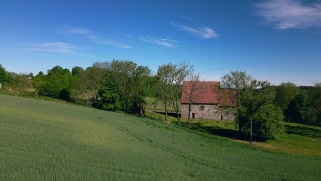 Raising drone over Berg Old Church (Berg steinkirke) with countryside fields in Larvik, Norway