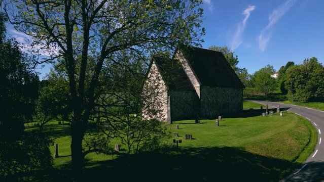 Aerial footage over Berg Old Church (Berg steinkirke) with countryside fields in Larvik, Norway