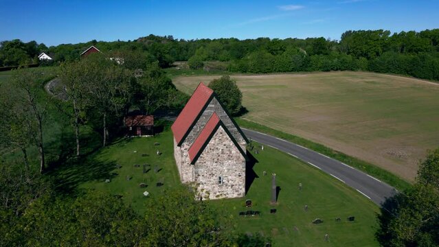 Drone footage of Berg Old Church (Berg steinkirke) with countryside and trees in Larvik, Norway