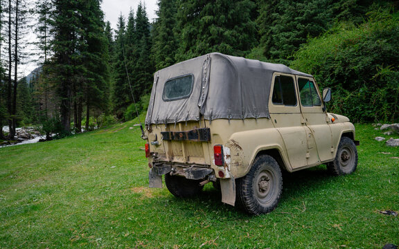 Journey to the mountains in an old Russian UAZ, crossing a river. Off-road adventure in the Kyrgyz mountains on a rainy day.