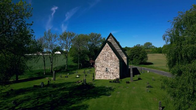 Drone footage of Berg Old Church (Berg steinkirke) with countryside lawns in Larvik, Norway