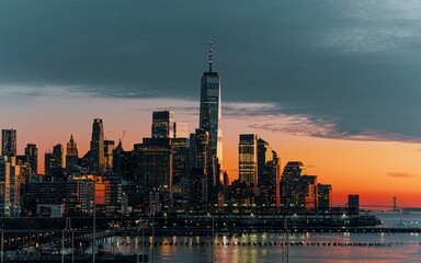 Scenic viewof New York City's downtown skyline, illuminated by the warm tones of the setting sun