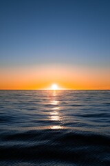 Vibrant vertical shot of the sun setting over the Atlantic Ocean