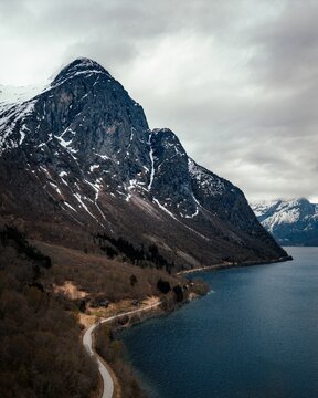 Snow-dusted mountain range, beside tranquil body of water, Eikesdalen, Norway