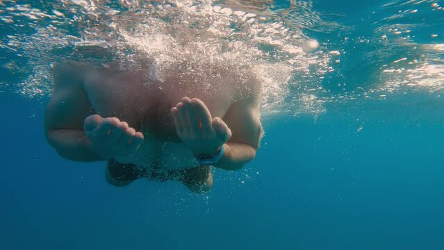 Boy is swimming breaststroke style in the open ocean underwater