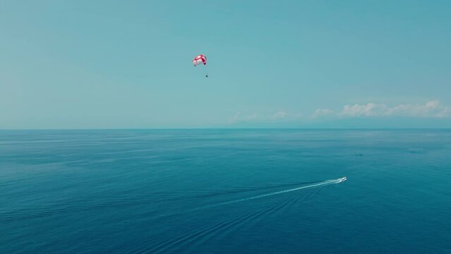4k 25fps footage: aerial view of the Caribbean sea of Calabria near Tropea and Capo Vaticano WITH A MOTORBOAT DRAGING A PARACHUTE WITH EXCITED AND FEAR TOURISTS ON BOARD