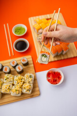 female hand holding chopsticks roll against the background of a set of rollers 2