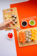 female hand holding chopsticks roll against the background of a set of rollers 1