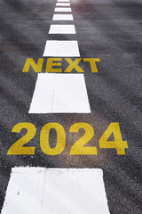 Next 2024 future opportunity concept and economic recovery idea. Next word written on asphalt road with white marking lines.