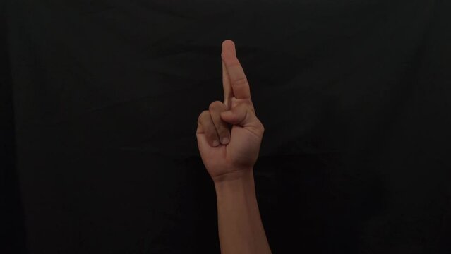 American sign language (ASL).A man's hand doing one-handed sign language used by deaf and dumb. man's hand doing Alphabet R sign language in 4K. R alphabet sign.
