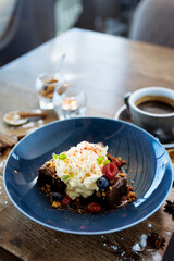 Brownie cake with salted caramel. Anglaise foam, raspberry sauce, praline nut and fresh berry. Delicious sweet dessert food closeup served for lunch in modern gourmet cuisine restaurant