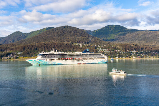 JUNEAU, ALASKA, USA - AUGUST 20, 2022: A passenger excursion vessel travels past the Norwegian Spirit cruise vessel on a scheduled itinerary stop and docked in Gastineau channel.