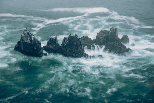 Aerial view of jagged rock formations on splashing water in Oregon