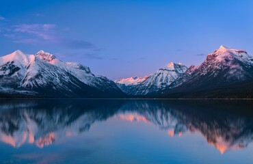 Early morning sunrise illuminating serene waters of Lake McDonald, Glacier National Park, Montana