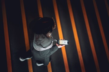 Overhead shot of a female crossing the street, listening to music on her phone
