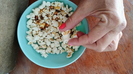 Hand holding popcorn in bowl 