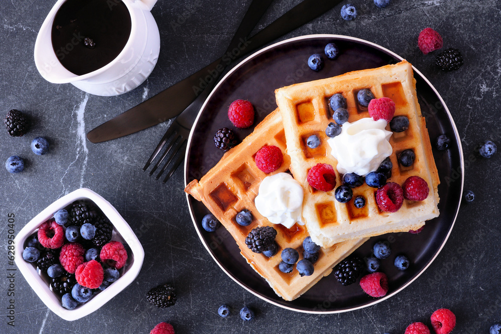 Poster breakfast waffles with berries and whipped cream. above view table scene over a dark stone backgroun