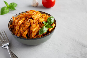 Homemade Tomato Pesto Pasta with Cheese and Basil in a Bowl, side view. Copy space.