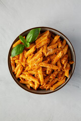 Homemade Tomato Pesto Pasta with Cheese and Basil in a Bowl, top view. Flat lay, overhead, from above.