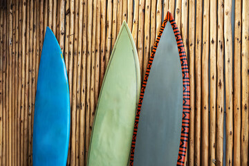 three worn surfboards against wall made of bamboo.