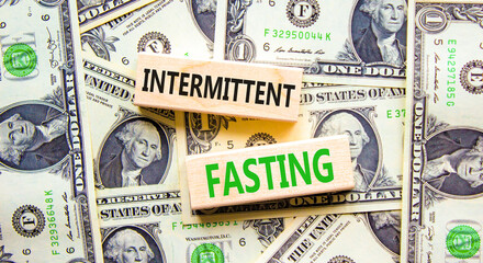 Intermittent fasting symbol. Concept words Intermittent fasting on wooden block. Beautiful background from dollar bills. Dollar bills. Healthy lifestyle intermittent fasting concept. Copy space.